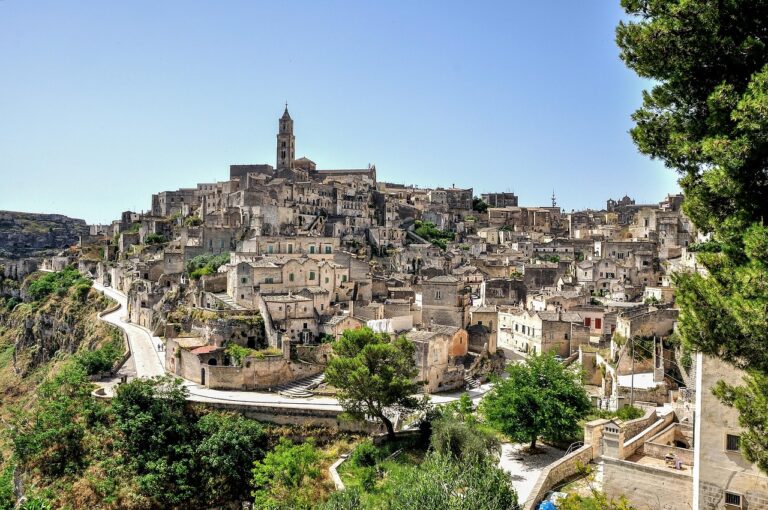 Vista panoramica sui Sassi di Matera da un paese lucano, con colline verdi e cielo sereno.