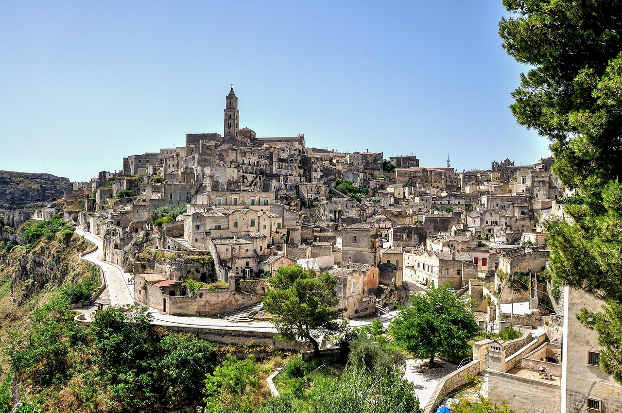 Vista panoramica sui Sassi di Matera da un paese lucano, con colline verdi e cielo sereno.