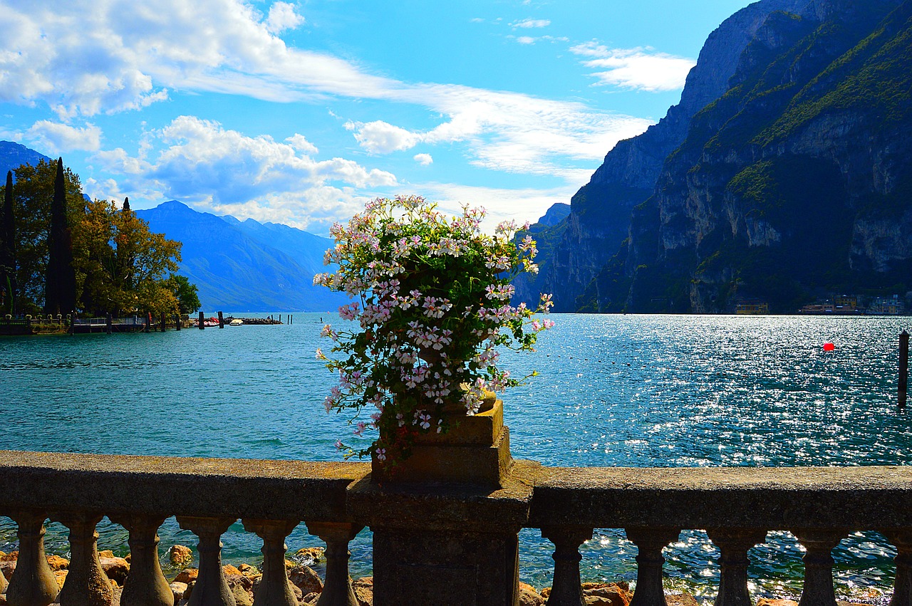 Panorama di un lago italiano in primavera, circondato da fiori colorati e alberi in fiore.
