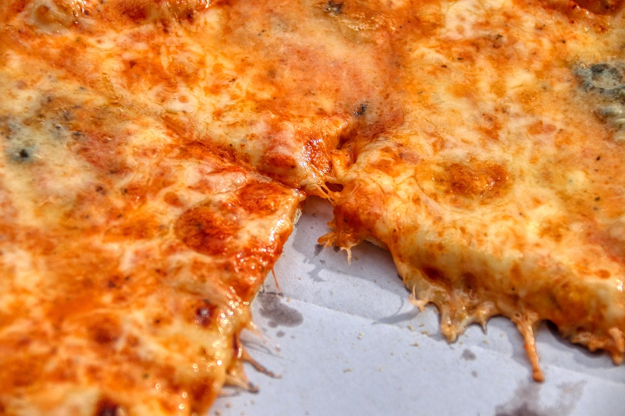 Pizza avanzata con segni di muffa e scolorimento su una fetta.