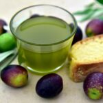 Olio extravergine di oliva versato in un bicchiere, con acqua accanto per il test di qualità.