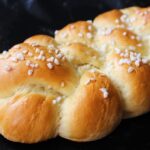 Brioche soffice su un piatto, con una fetta tagliata e una decorazione di zucchero a velo.