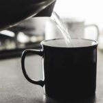 Uomo che beve acqua calda al mattino, con focus su salute, colesterolo e glicemia.