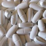 Integratore di magnesio su un tavolo, con un orologio che segna l'ora indicata nell'articolo.