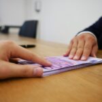 Uomo anziano sorride mentre legge un documento bancario, rappresentando la riduzione delle spese.