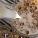Un bicchiere di latte d'avena con cereali e frutta su un tavolo per colazione.