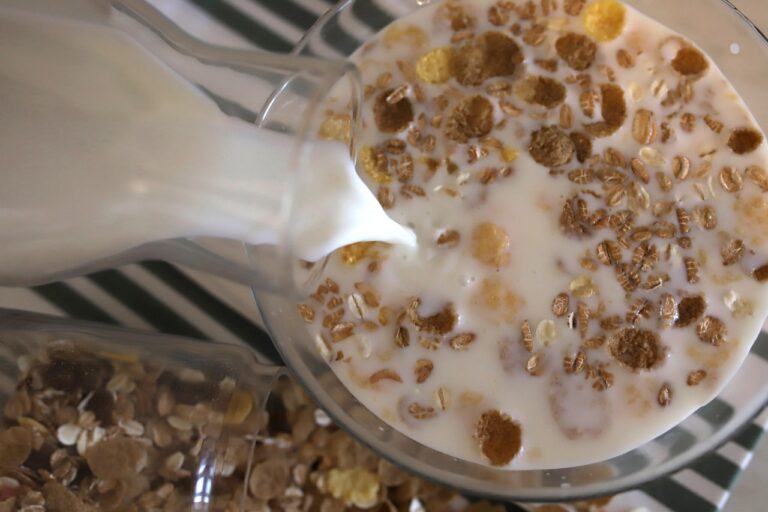 Un bicchiere di latte d'avena con cereali e frutta su un tavolo per colazione.